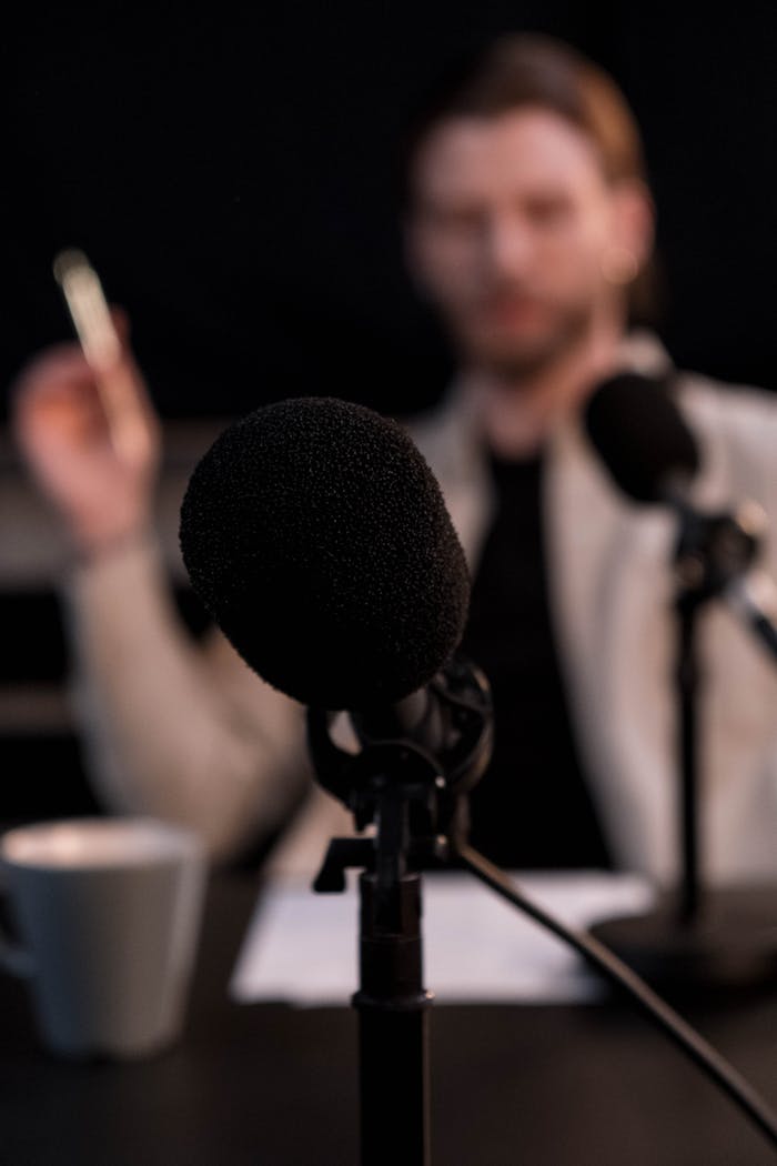 our-journey-03 Close-up of a microphone with a blurred background, ideal for podcast themes.